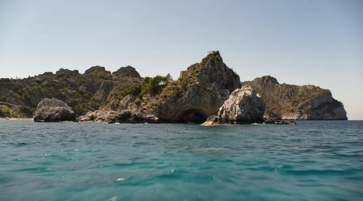 Isola Bella near Taormina seen from a boat, with clear turquoise water and the green headland behind