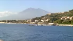 The bay of Giardini Naxos seen from the sea, with the coast below Taormina and Etna in the distance
