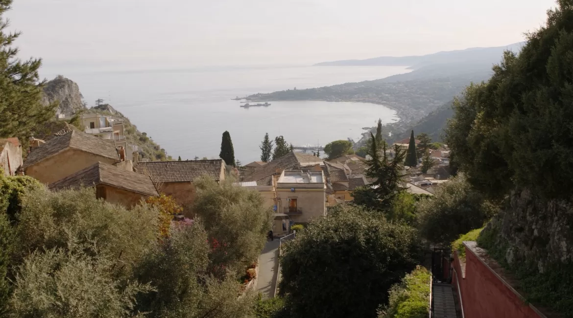 View over Taormina old town rooftops down to the blue coastline and Isola Bella below