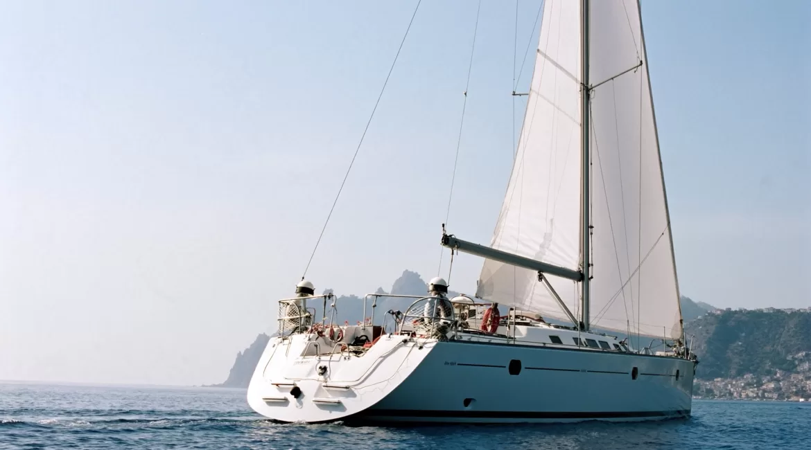 A yacht on one of the sailing trips from Giardini Naxos under full sail off the Taormina coast