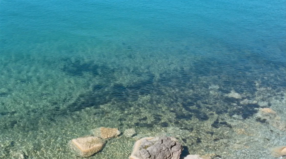 The clearest water near Taormina: transparent turquoise sea over pale rock and pebbles in a cove