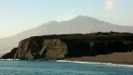 Giardini Naxos by boat: the black lava headland of Capo Schiso with Etna rising behind it
