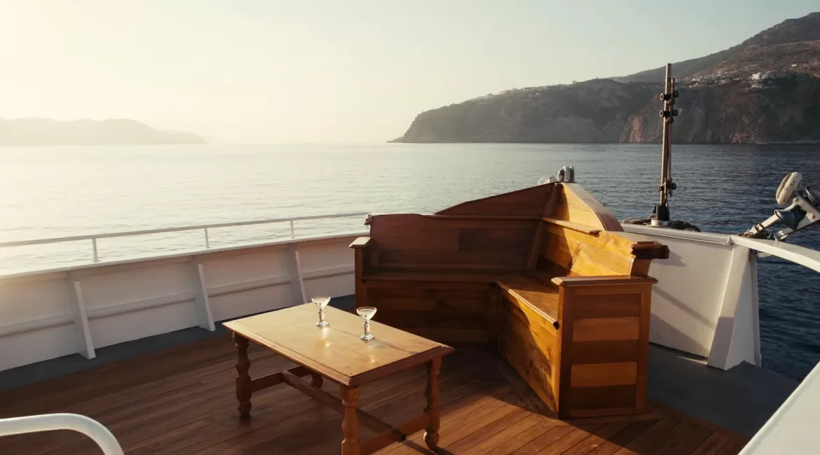 A private boat day in Taormina: an empty boat deck and glasses on the table in warm late light