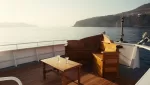 A private boat day in Taormina: an empty boat deck and glasses on the table in warm late light