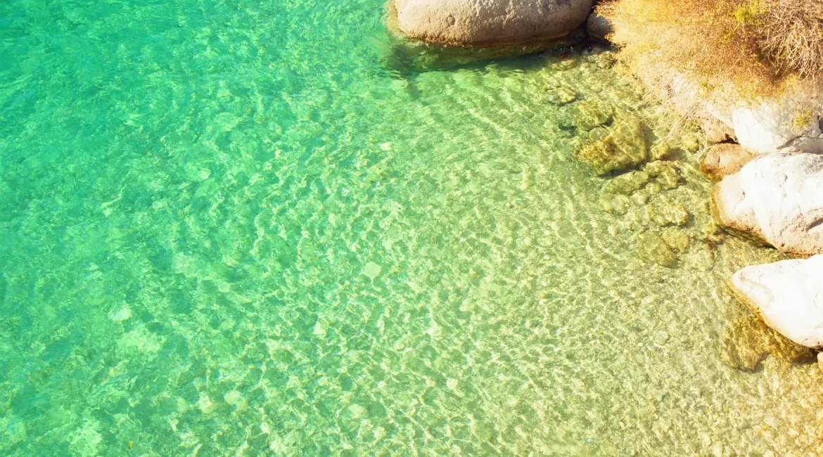 Sea temperature near Taormina in autumn: clear warm water over pale rocks in a quiet cove