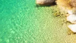 Sea temperature near Taormina in autumn: clear warm water over pale rocks in a quiet cove