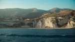 Taormina in October seen from the water, with soft autumn light on the cliffs and an empty coastline